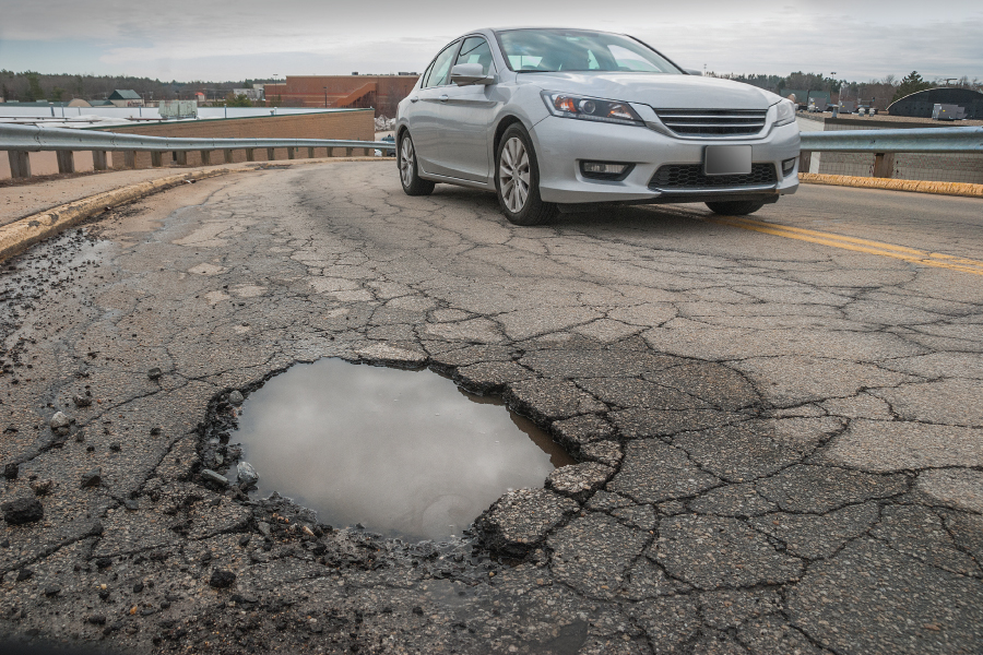 car driving close to a pothole filled with water