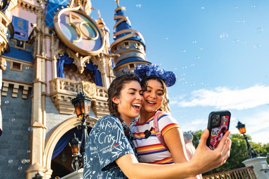 girls taking picture in front of Cinderella's castle in Magic Kingdom at Walt Disney World